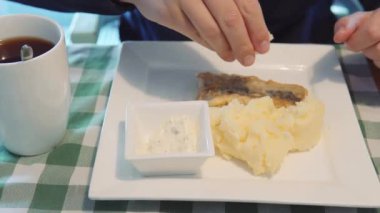 Male hands squeeze lemon on fried fish fillet of pollock or whiting fish for lunch in a restaurant. Close-up.