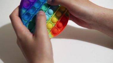 A man plays a popular trending pop toy for children, a multi-colored silicone circle with bubbles. 4k footage.
