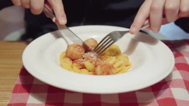 A man eats Italian pasta with chicken meatballs and tomato sauce. Close-up shot in 4k.