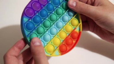 Mens hands rotate the popular silicone anti-stress toy pop it, a multi-colored tactile trendy toy.