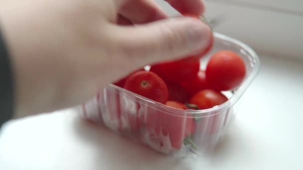スマートウォッチを手にしたメンズは プラスチック製の箱から熟したカクテルトマトをピックアップして表示します 有機健康製品のコンセプト — ストック動画