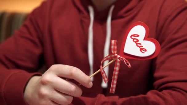 愛と献身のシンボル バレンタインデーの休日は 白人男性の人間の手の中に木製の棒に心臓の形でクローズアップ表示されます 赤と白のDiy手作りの贈り物 高品質 — ストック動画