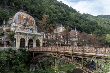 Baile Herculane Herculane Banyo, Romanya 3 Eylül 2022: İmparatorluk Hamamları veya Neptun Hamamları ve eski metal köprü, UNESCO Dünya Mirası Alanı, Romanya 'nın Baile Herculane kentinin eski bölgesinde yer alıyor.. 