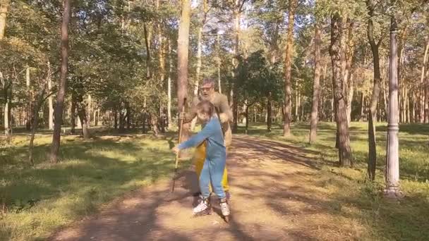 Little Girl Rollerblading Park Her Old Grandfather Holding Her Hand — Stock Video