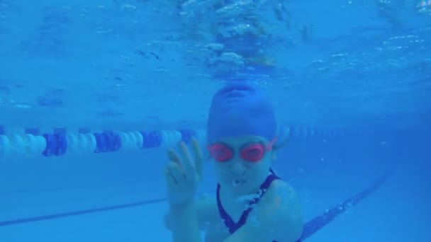 少女はプールで水中で泳いでいる 水中でのスローモーション人間 子供は水中で泳ぐことを学ぶ — ストック動画