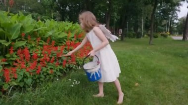 Sırtında kanatları olan tatlı melek kız. Elinde boyadığı bir kova boya var..