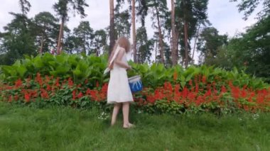 Sırtında kanatları olan tatlı melek kız. Elinde boyadığı bir kova boya var..