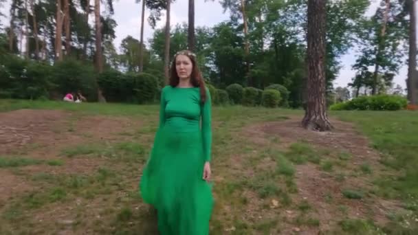 公園の芝生の上を緑のドレスの妖精の女性が歩いている — ストック動画