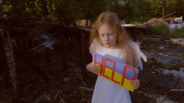 Elinde poster olan bir kız çocukları korumak istiyor. Savaştan kalma yanmış bir evin arka planına karşı..