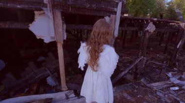 Yanmış bir evin arka planında üzgün bir kız çocuğu. Yıkılmış evin yanındaki çocuk melek..
