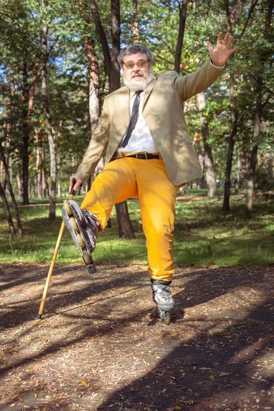 有趣的老人是在公园里滑冰 一个拿着手杖跳舞和做鬼脸的活跃的祖父 有白胡子的爷爷 — 图库照片