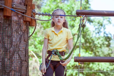 İplerden yapılmış bir orman macera parkındaki çocuk. Çocukların açık hava tırmanış eğlence merkezi. Çocuklar için oyun alanı ve kablolu spor. Spor askıya alınmış halat eğitmeni.