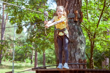 İplerden yapılmış bir orman macera parkındaki çocuk. Çocukların açık hava tırmanış eğlence merkezi. Çocuklar için oyun alanı ve kablolu spor. Spor askıya alınmış halat eğitmeni.
