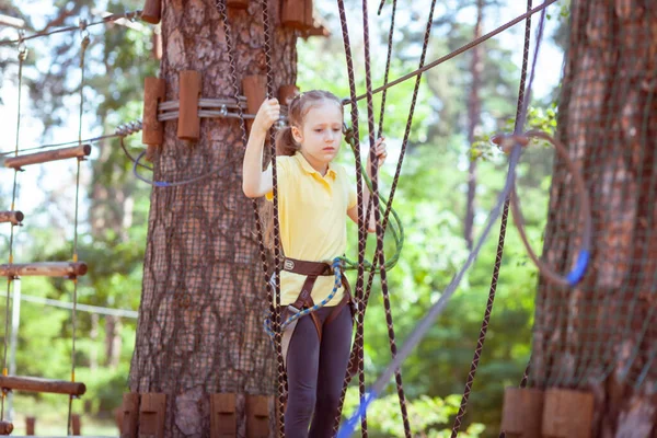 İplerden yapılmış bir orman macera parkındaki çocuk. Çocukların açık hava tırmanış eğlence merkezi. Çocuklar için oyun alanı ve kablolu spor. Spor askıya alınmış halat eğitmeni.