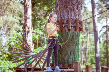 İplerden yapılmış bir orman macera parkındaki çocuk. Çocukların açık hava tırmanış eğlence merkezi. Çocuklar için oyun alanı ve kablolu spor. Spor askıya alınmış halat eğitmeni.
