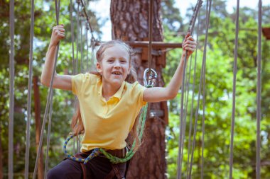 İplerden yapılmış bir orman macera parkındaki çocuk. Çocukların açık hava tırmanış eğlence merkezi. Çocuklar için oyun alanı ve kablolu spor. Spor askıya alınmış halat eğitmeni.