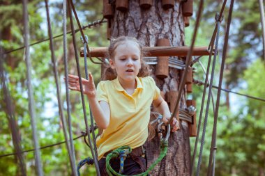 İplerden yapılmış bir orman macera parkındaki çocuk. Çocukların açık hava tırmanış eğlence merkezi. Çocuklar için oyun alanı ve kablolu spor. Spor askıya alınmış halat eğitmeni.