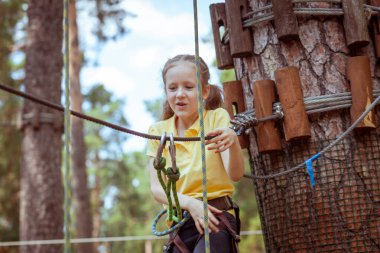 İplerden yapılmış bir orman macera parkındaki çocuk. Çocukların açık hava tırmanış eğlence merkezi. Çocuklar için oyun alanı ve kablolu spor. Spor askıya alınmış halat eğitmeni.