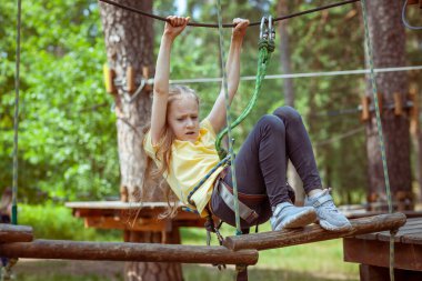 İplerden yapılmış bir orman macera parkındaki çocuk. Çocukların açık hava tırmanış eğlence merkezi. Çocuklar için oyun alanı ve kablolu spor. Spor askıya alınmış halat eğitmeni.