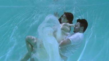 Bir kadın ve bir adam suyun altında yüzüyorlar. Bir kadın bir erkeği suyun altında öper..