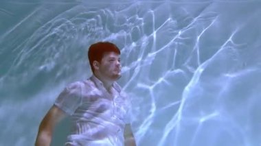 Elbiseli adam suyun altında debelenir. Suya batar..