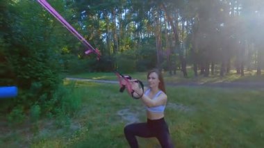 Bir kadın lastik bir spor simülatöründe elastik bant esnetiyor. Spor kas eğitimi için lastik bant..
