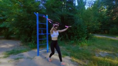 Bir kadın lastik bir spor simülatöründe elastik bant esnetiyor. Spor kas eğitimi için lastik bant..