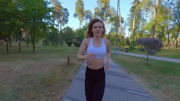 公園のトレーニングカーディオで走る運動女性 ジョギングは重い負荷の前にウォームアップです 公園で屋外で走ることは女性にとって有益です — ストック動画