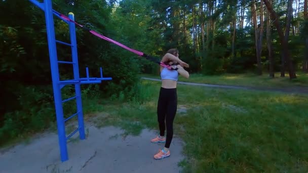 Eine Frau Sitzt Einem Sport Gummisimulator Und Dehnt Ein Gummiband — Stockvideo
