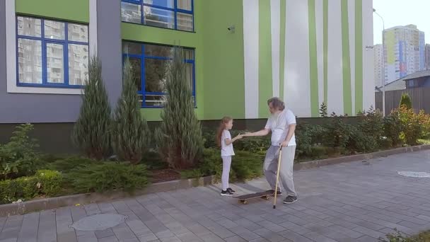 Ein Mädchen Bringt Einem Alten Mann Das Skateboardfahren Bei Sie — Stockvideo