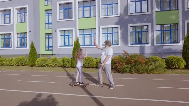 Kind Meisje Leert Een Oude Man Een Skateboard Rijden Trainen — Stockvideo