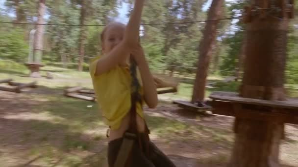 一个小孩在森林探险公园里用绳子做的这个女孩正用一根高绳爬上小路 儿童户外攀爬娱乐中心 儿童游乐场和有缆车的运动场 — 图库视频影像