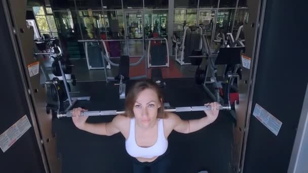 ボディービルの機械のジムの列車の女性 女性はシミュレーターに筋肉をポンプで送ります スポーツマシンの女性ボディのトレーニング — ストック動画