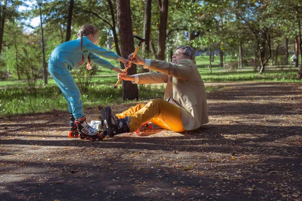 Een Meisje Rolschaatst Het Park Met Haar Oude Opa Een Stockafbeelding