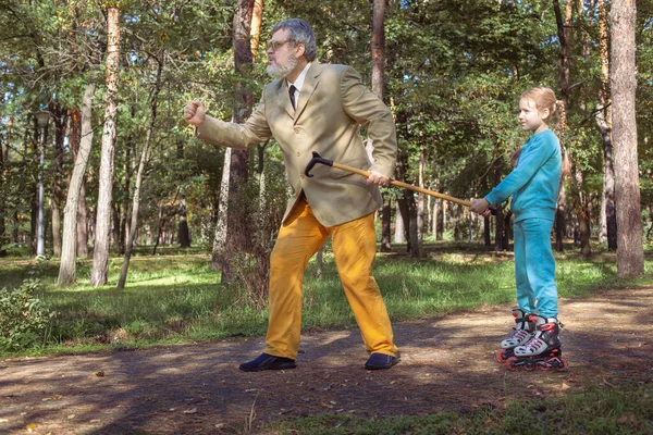 Grootvader Loopt Met Zijn Kleindochter Het Park Een Meisje Rolschaatst Stockfoto
