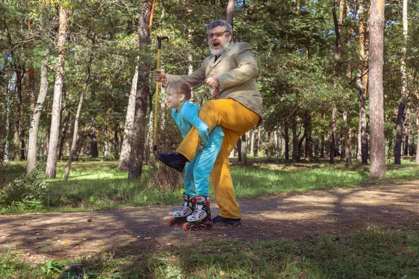 Grootvader Loopt Met Zijn Kleindochter Het Park Een Meisje Rolschaatst Stockafbeelding