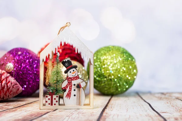 Vánoční Ozdoba Sněhulák Strom Dřevěném Domě Lesklými Koulemi Dřevěném Stole — Stock fotografie