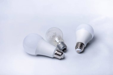 Beyaz arka planda üç tane elektrik lambası. Enerji tasarrufu lambaları ve tungsten filament lambası