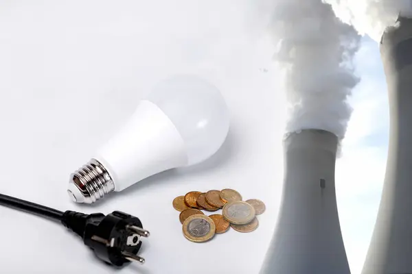 Plug, light bulb, coins and fuming chimneys of a power plant. Electricity consumption and environmental pollution