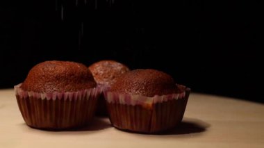 Siyah arkaplanda pudra şekeri serpiştirilmiş muffinler