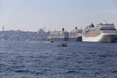 22 Ekim 2023 İstanbul, Türkiye. Boğaz, Galataport 'ta yolcu gemileri ve turistlerle birlikte yüzen küçük gemiler. Arka planda büyük bir cami.