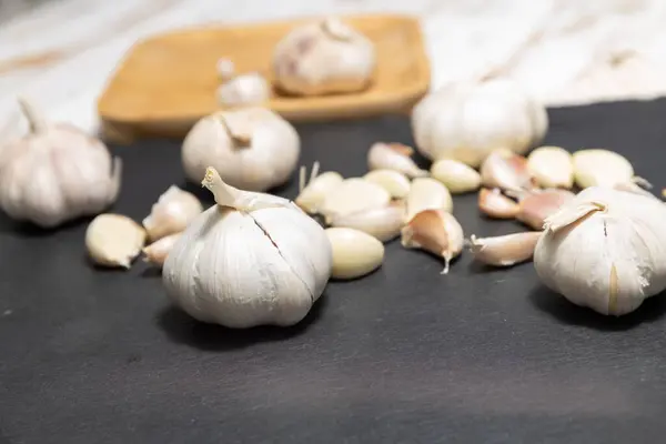 Ripe garlic on black stone plate. Unpeeled garlic, healthy food from nature