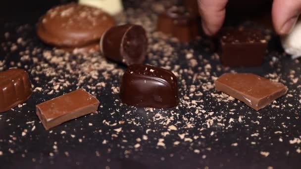Choklad Bitar Mjölkchoklad Sten Svart Tallrik Och Hand Med Choklad — Stockvideo