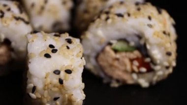 Suşi rulolarını somon salatası ve kızarmış siyah-beyaz susam tohumlarıyla taş bir levhada kapatıyoruz.