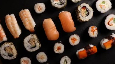  Suşi nigiri ve çiğ Atlantik somonuyla dönen tabak, siyah tabakta değişik türde hosomaki suşisi..