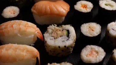 Suşi nigiri, çiğ Atlantik somonuyla, çeşitli türde hosomaki suşisi, siyah tabakta..