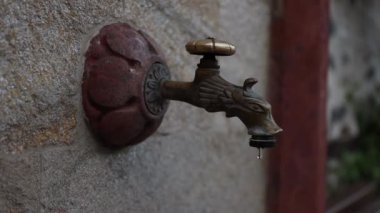 Eski metal bir musluktan su damlıyor. Su kaynakları tasarrufu, küresel kuraklık