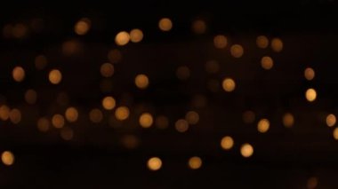 Odaklanmamış turuncu ışıklar karanlıkta yanıp sönüyor. Koyu arkaplanda turuncu bokeh