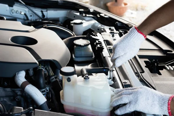 Automotive and car repair shops services by professional engine maintenance technicians. Auto mechanic using Socket wrench repair tools checking car. Mechanic tightening a spark plug into place.