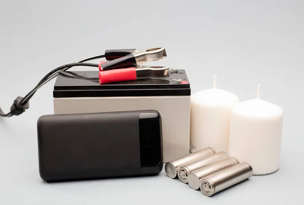 stock image emergency power set, power bank with batteries, white candles and battery with connection bolts gray background